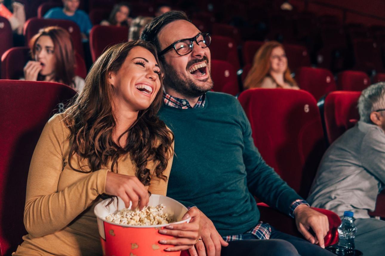 Smiling couple eating popcorn at cinema